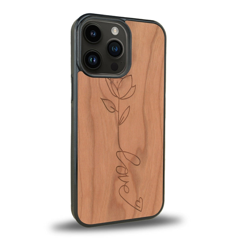 Coque de protection en bois véritable fabriquée en France pour iPhone 15 Pro + MagSafe® sur le thème de la fête des mères avec un motif représentant une fleur dont la tige forme le mot "love"