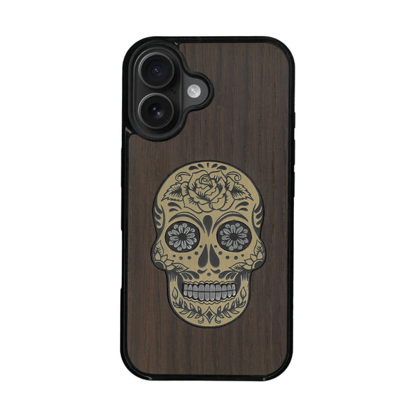 Coque de protection en bois véritable fabriquée en France pour iPhone 16 Plus alliant du chêne fumé avec du métal argenté et doré représentant une tête de mort mexicaine sur le thème Dia de los Muertos