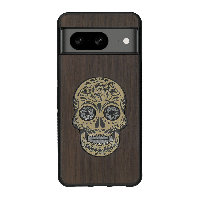 Coque de protection en bois véritable fabriquée en France pour Google Pixel 7A alliant du chêne fumé avec du métal argenté et doré représentant une tête de mort mexicaine sur le thème Dia de los Muertos