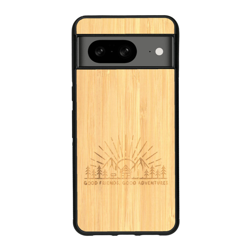 Coque de protection en bois véritable fabriquée en France pour Google Pixel 7A sur le thème chill et nature avec un motif représentant un levé de soleil sur un paysage de montagne avec des sapins et un chalet et la phrase "Good friends, good adventure"