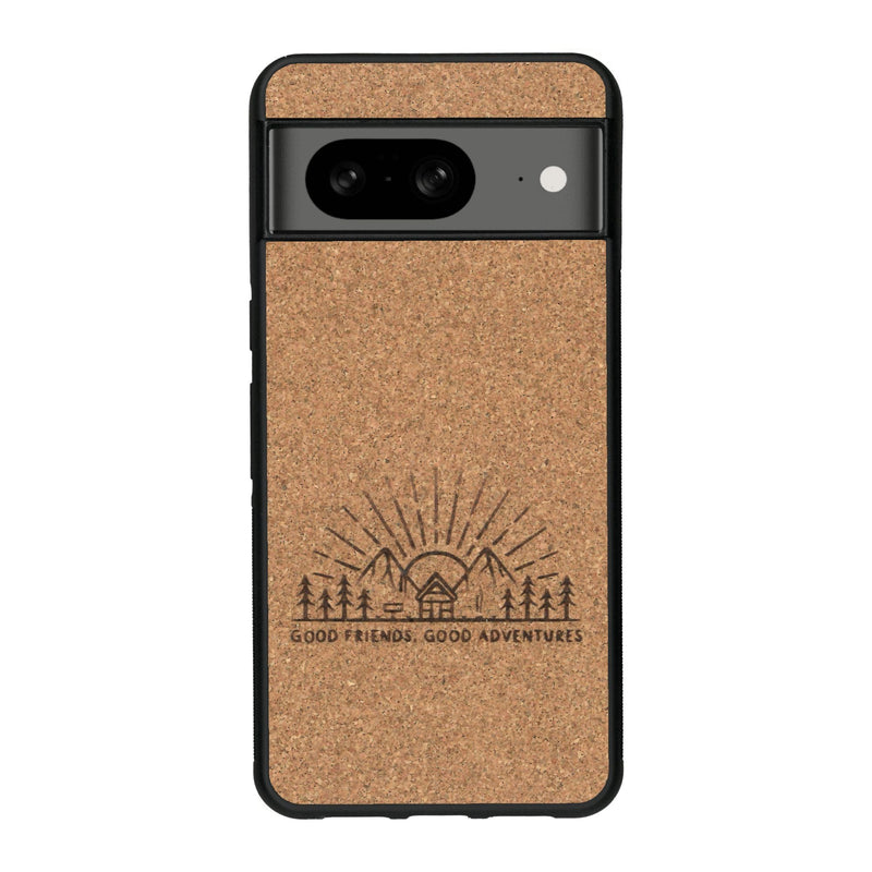 Coque de protection en bois véritable fabriquée en France pour Google Pixel 7A sur le thème chill et nature avec un motif représentant un levé de soleil sur un paysage de montagne avec des sapins et un chalet et la phrase "Good friends, good adventure"