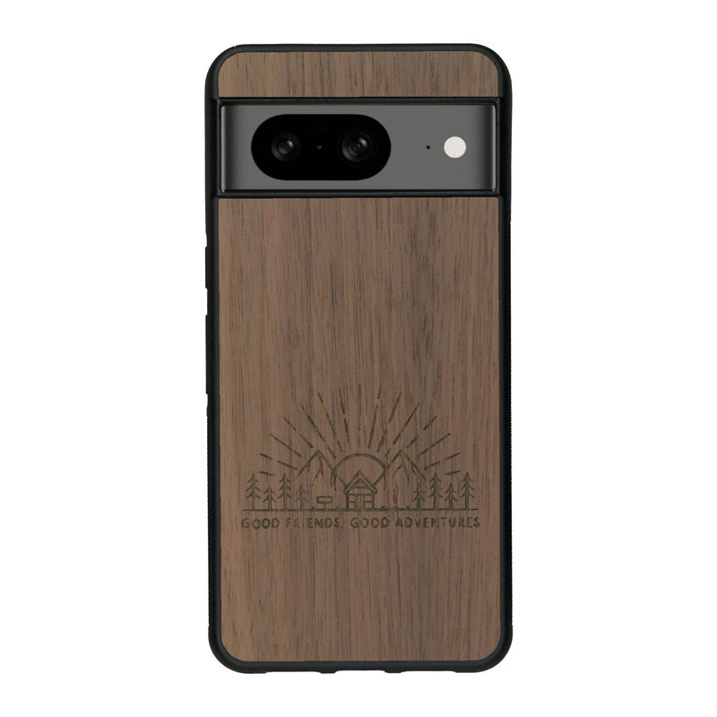 Coque de protection en bois véritable fabriquée en France pour Google Pixel 7A sur le thème chill et nature avec un motif représentant un levé de soleil sur un paysage de montagne avec des sapins et un chalet et la phrase "Good friends, good adventure"