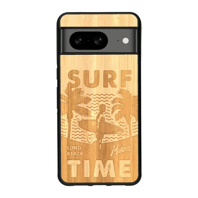 Coque de protection en bois véritable fabriquée en France pour Google Pixel 7A sur le thème chill avec un motif représentant une silouhette tenant une planche de surf sur une plage entouré de palmiers et les mots "Surf Time Long Beach Miami"