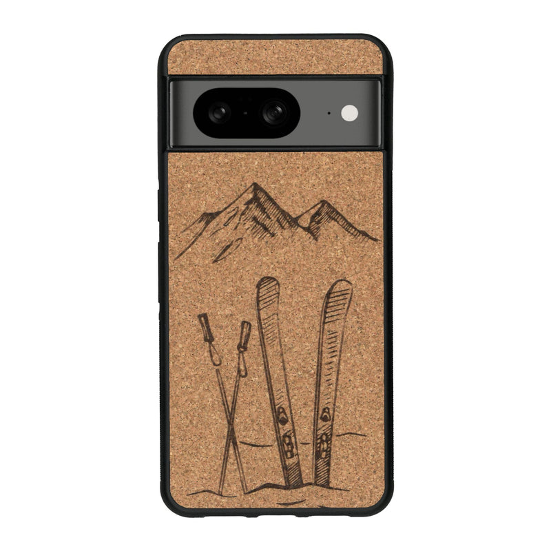 Coque de protection en bois véritable fabriquée en France pour Google Pixel 7A sur le thème de la montagne, du ski et de la neige avec un motif représentant une paire de ski plantée dans la neige avec en fond des montagnes enneigées