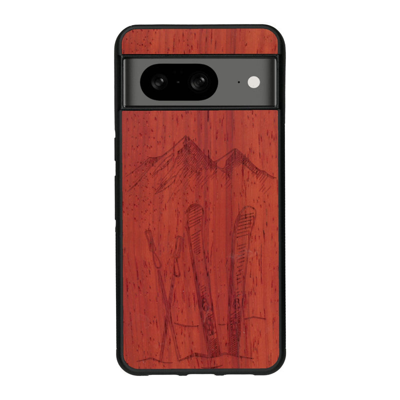 Coque de protection en bois véritable fabriquée en France pour Google Pixel 7A sur le thème de la montagne, du ski et de la neige avec un motif représentant une paire de ski plantée dans la neige avec en fond des montagnes enneigées