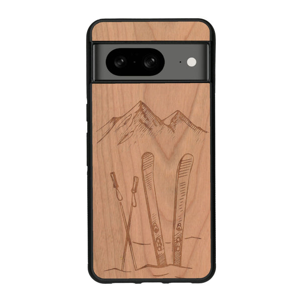 Coque de protection en bois véritable fabriquée en France pour Google Pixel 8A sur le thème de la montagne, du ski et de la neige avec un motif représentant une paire de ski plantée dans la neige avec en fond des montagnes enneigées