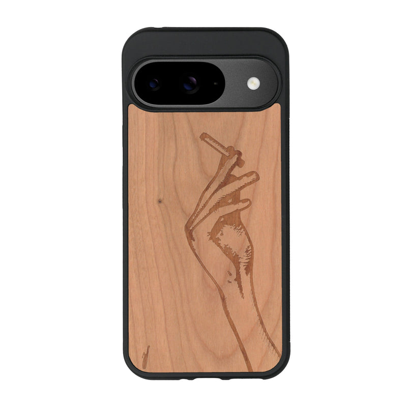 Coque de protection en bois véritable fabriquée en France pour Google Pixel 9 représentant une main de femme tenant une cigarette de type line art en collaboration avec l'artiste Maud Dabs