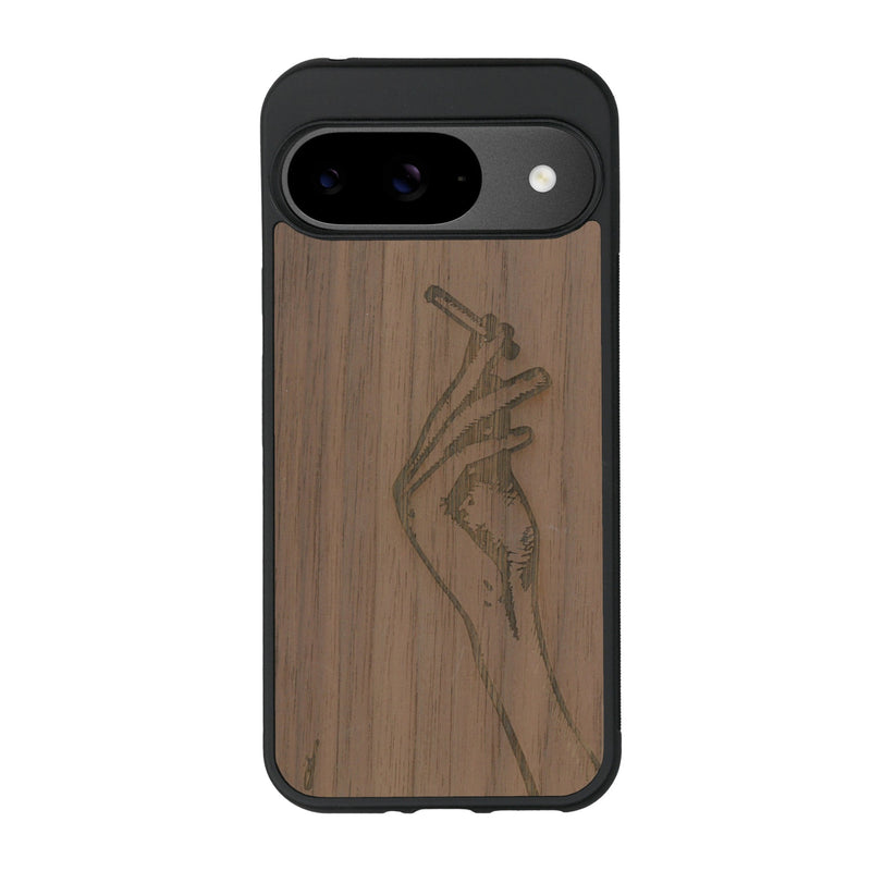 Coque de protection en bois véritable fabriquée en France pour Google Pixel 9 représentant une main de femme tenant une cigarette de type line art en collaboration avec l'artiste Maud Dabs