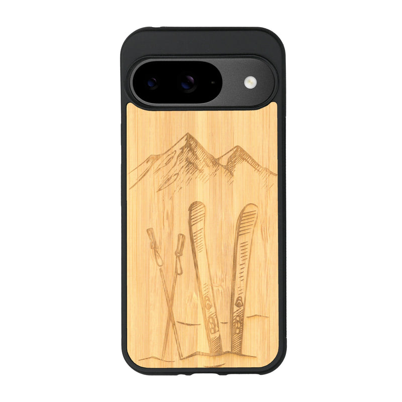 Coque de protection en bois véritable fabriquée en France pour Google Pixel 9 Pro sur le thème de la montagne, du ski et de la neige avec un motif représentant une paire de ski plantée dans la neige avec en fond des montagnes enneigées