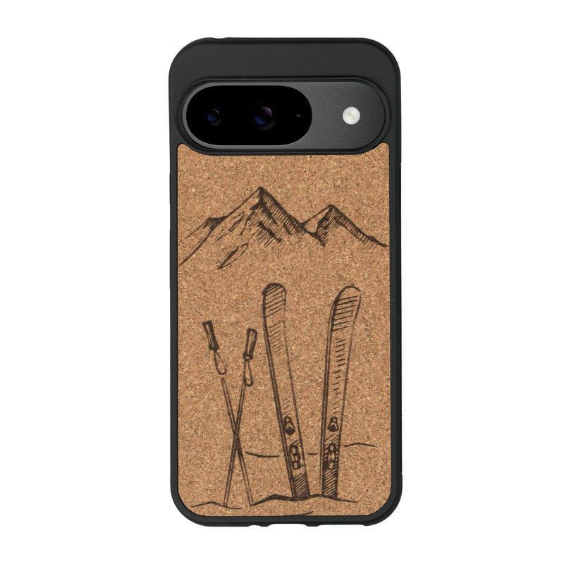 Coque de protection en bois véritable fabriquée en France pour Google Pixel 9 Pro sur le thème de la montagne, du ski et de la neige avec un motif représentant une paire de ski plantée dans la neige avec en fond des montagnes enneigées