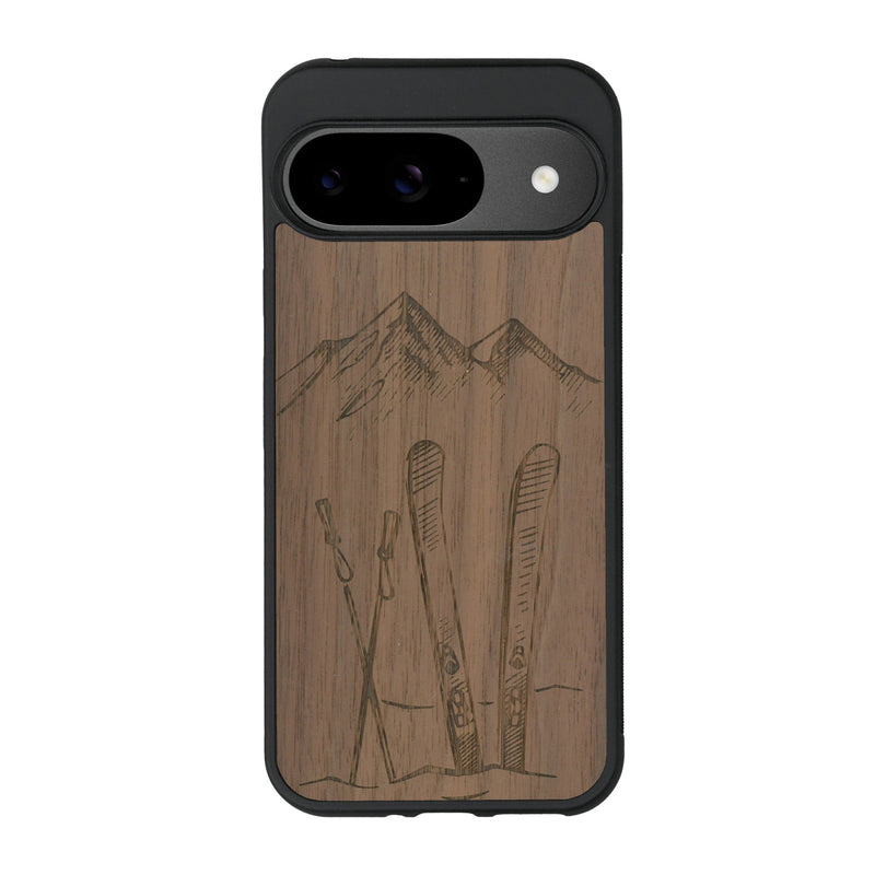 Coque de protection en bois véritable fabriquée en France pour Google Pixel 9 Pro sur le thème de la montagne, du ski et de la neige avec un motif représentant une paire de ski plantée dans la neige avec en fond des montagnes enneigées