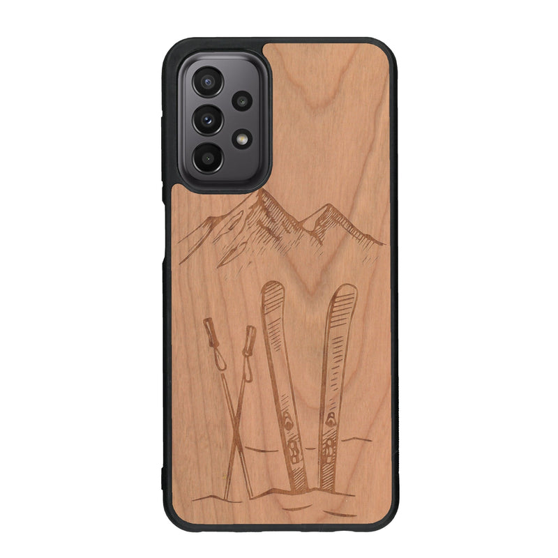 Coque de protection en bois véritable fabriquée en France pour Samsung A33 sur le thème de la montagne, du ski et de la neige avec un motif représentant une paire de ski plantée dans la neige avec en fond des montagnes enneigées