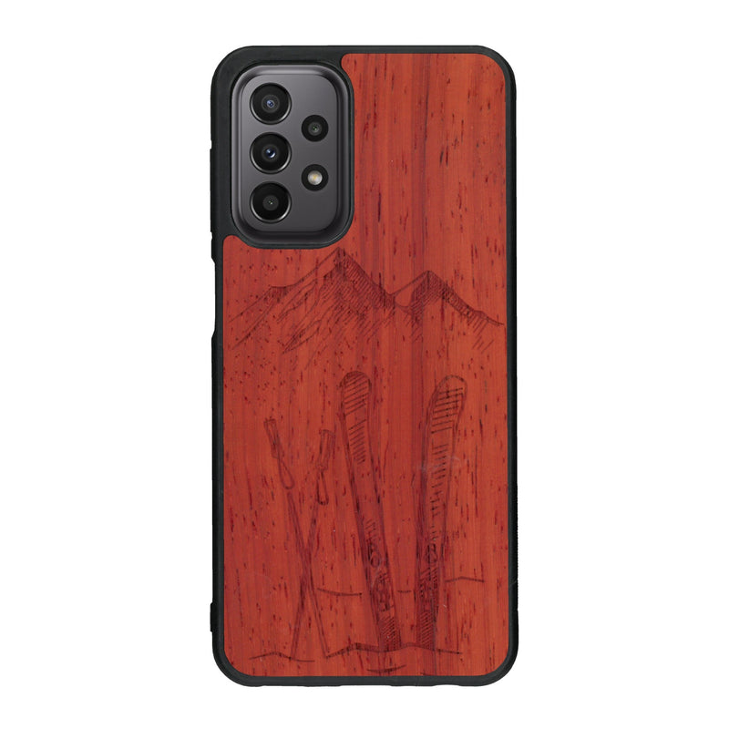 Coque de protection en bois véritable fabriquée en France pour Samsung A33 sur le thème de la montagne, du ski et de la neige avec un motif représentant une paire de ski plantée dans la neige avec en fond des montagnes enneigées