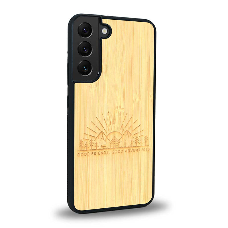 Coque de protection en bois véritable fabriquée en France pour Samsung S24 sur le thème chill et nature avec un motif représentant un levé de soleil sur un paysage de montagne avec des sapins et un chalet et la phrase "Good friends, good adventure"