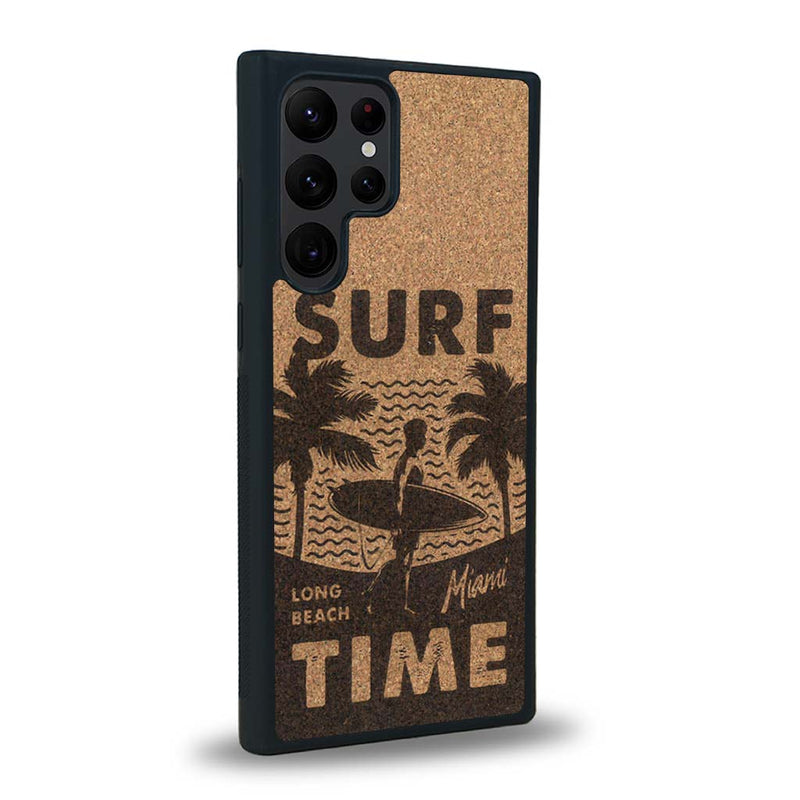 Coque de protection en bois véritable fabriquée en France pour Samsung S24 Ultra sur le thème chill avec un motif représentant une silouhette tenant une planche de surf sur une plage entouré de palmiers et les mots "Surf Time Long Beach Miami"