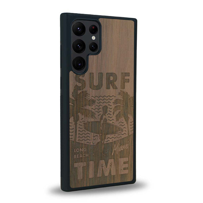 Coque de protection en bois véritable fabriquée en France pour Samsung S24 Ultra sur le thème chill avec un motif représentant une silouhette tenant une planche de surf sur une plage entouré de palmiers et les mots "Surf Time Long Beach Miami"