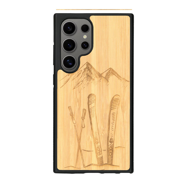 Coque de protection en bois véritable fabriquée en France pour Samsung S24 Ultra sur le thème de la montagne, du ski et de la neige avec un motif représentant une paire de ski plantée dans la neige avec en fond des montagnes enneigées