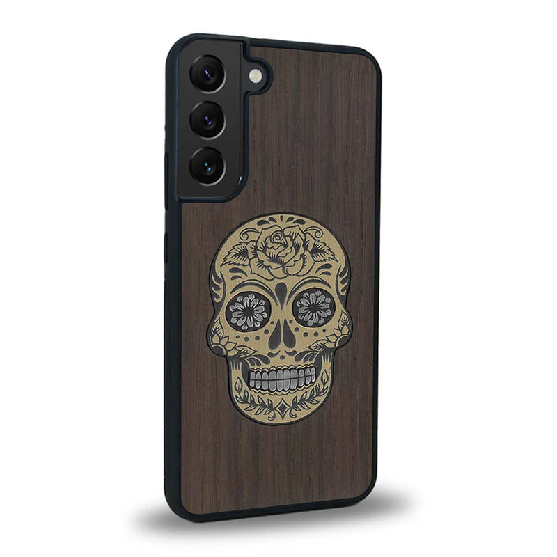 Coque de protection en bois véritable fabriquée en France pour Samsung S24+ alliant du chêne fumé avec du métal argenté et doré représentant une tête de mort mexicaine sur le thème Dia de los Muertos