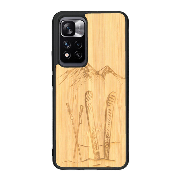 Coque de protection en bois véritable fabriquée en France pour Xiaomi Redmi Note 11 5G sur le thème de la montagne, du ski et de la neige avec un motif représentant une paire de ski plantée dans la neige avec en fond des montagnes enneigées