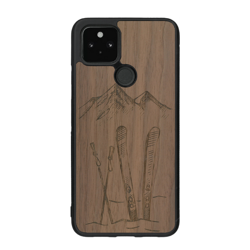 Coque de protection en bois véritable fabriquée en France pour Google Pixel 4A sur le thème de la montagne, du ski et de la neige avec un motif représentant une paire de ski plantée dans la neige avec en fond des montagnes enneigées