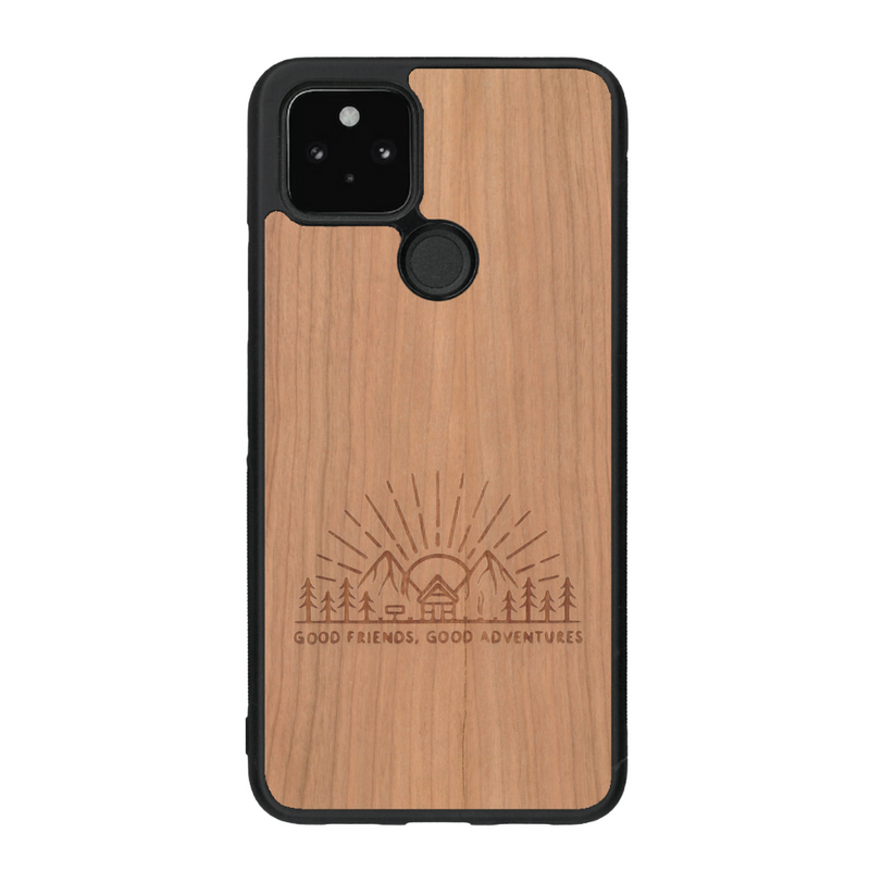 Coque de protection en bois véritable fabriquée en France pour Google Pixel 5a sur le thème chill et nature avec un motif représentant un levé de soleil sur un paysage de montagne avec des sapins et un chalet et la phrase "Good friends, good adventure"