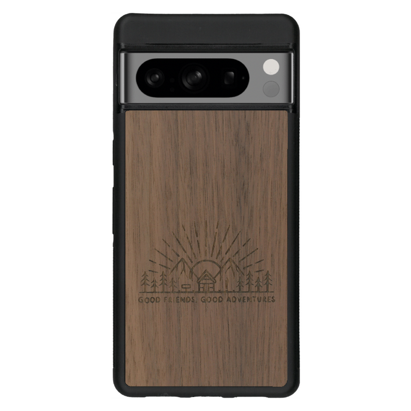 Coque de protection en bois véritable fabriquée en France pour Google Pixel 7 sur le thème chill et nature avec un motif représentant un levé de soleil sur un paysage de montagne avec des sapins et un chalet et la phrase "Good friends, good adventure"