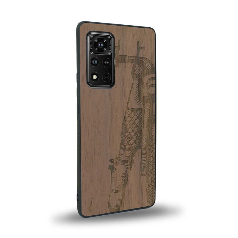 Coque de protection en bois véritable fabriquée en France pour Honor V40 représentant une vue de face d'une femme sur une moto vintage dessinée à la main par l'artiste Maud Dabs