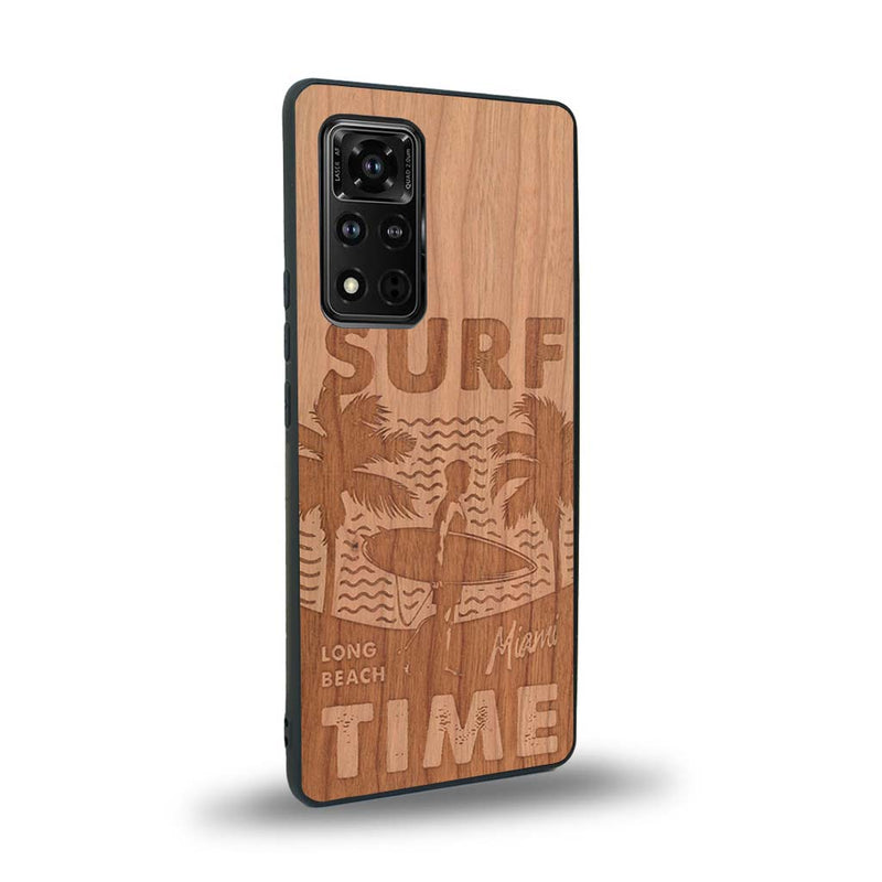 Coque de protection en bois véritable fabriquée en France pour Honor V40 sur le thème chill avec un motif représentant une silouhette tenant une planche de surf sur une plage entouré de palmiers et les mots "Surf Time Long Beach Miami"