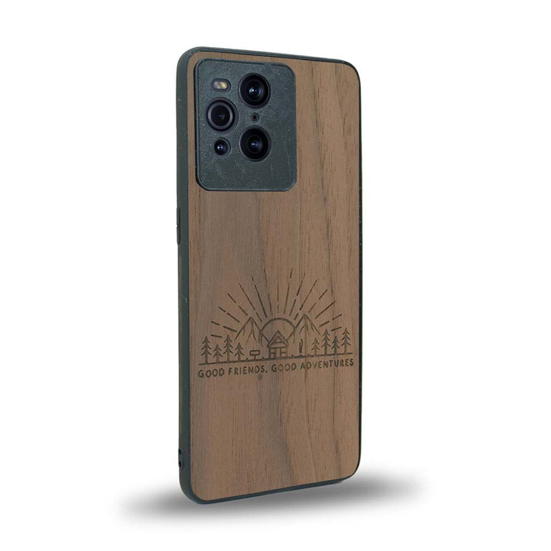 Coque de protection en bois véritable fabriquée en France pour Oppo Find X3 Pro sur le thème chill et nature avec un motif représentant un levé de soleil sur un paysage de montagne avec des sapins et un chalet et la phrase "Good friends, good adventure"