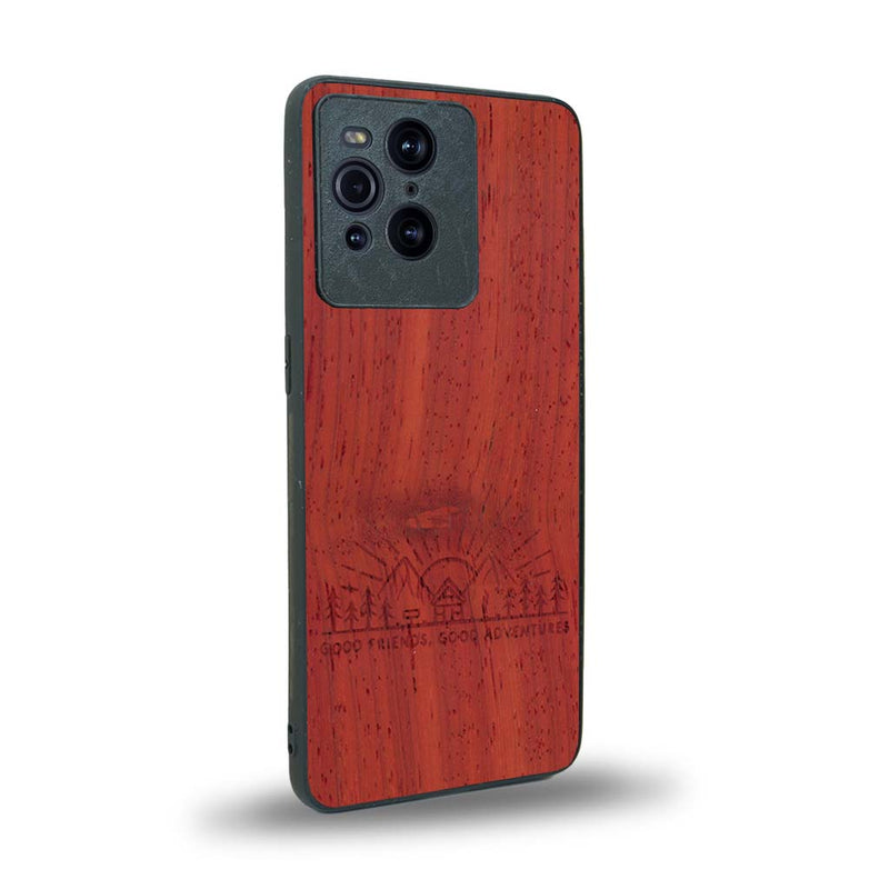 Coque de protection en bois véritable fabriquée en France pour Oppo Find X3 Pro sur le thème chill et nature avec un motif représentant un levé de soleil sur un paysage de montagne avec des sapins et un chalet et la phrase "Good friends, good adventure"