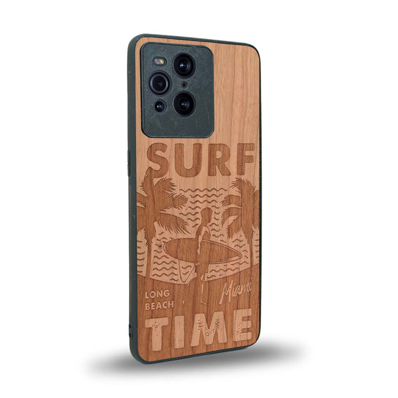 Coque de protection en bois véritable fabriquée en France pour Oppo Find X3 Pro sur le thème chill avec un motif représentant une silouhette tenant une planche de surf sur une plage entouré de palmiers et les mots "Surf Time Long Beach Miami"