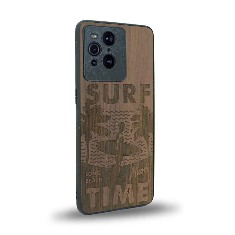 Coque de protection en bois véritable fabriquée en France pour Oppo Find X3 Pro sur le thème chill avec un motif représentant une silouhette tenant une planche de surf sur une plage entouré de palmiers et les mots "Surf Time Long Beach Miami"