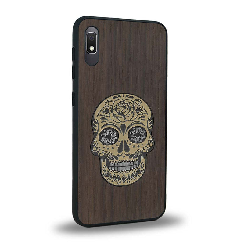 Coque de protection en bois véritable fabriquée en France pour Samsung A10 alliant du chêne fumé avec du métal argenté et doré représentant une tête de mort mexicaine sur le thème Dia de los Muertos