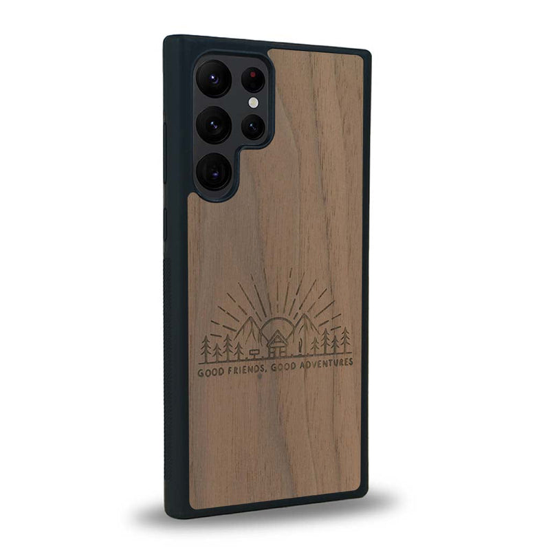 Coque de protection en bois véritable fabriquée en France pour Samsung S23 Ultra sur le thème chill et nature avec un motif représentant un levé de soleil sur un paysage de montagne avec des sapins et un chalet et la phrase "Good friends, good adventure"