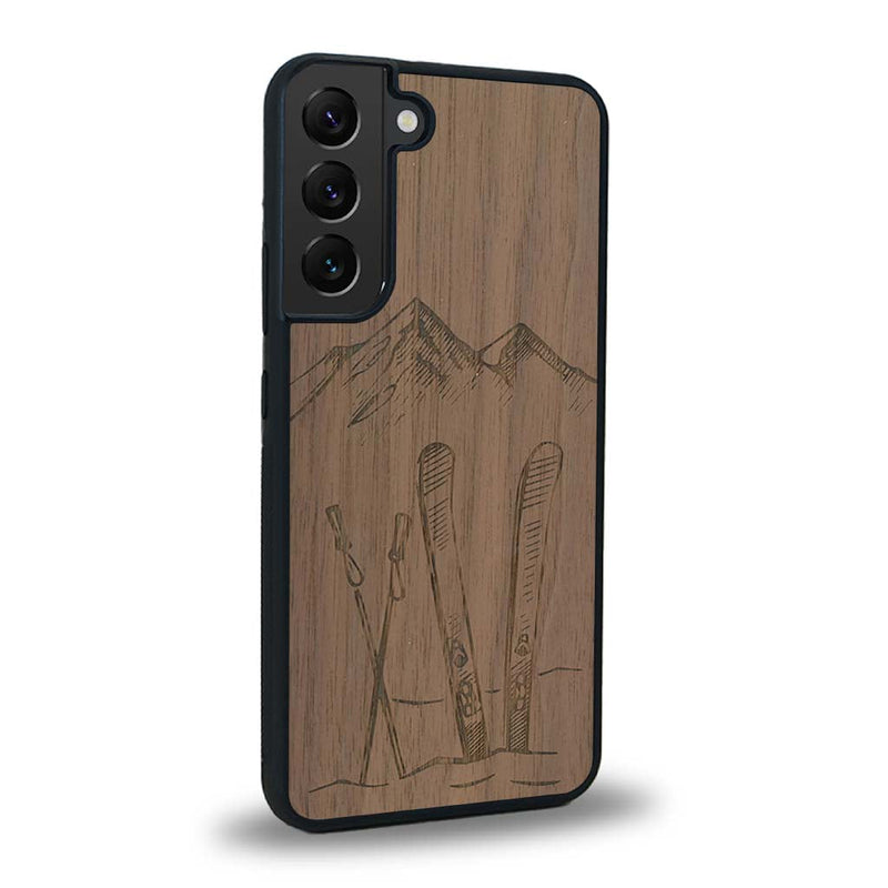 Coque de protection en bois véritable fabriquée en France pour Samsung S23 sur le thème de la montagne, du ski et de la neige avec un motif représentant une paire de ski plantée dans la neige avec en fond des montagnes enneigées