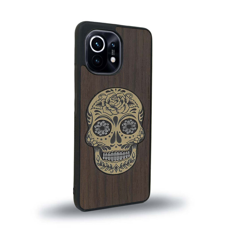 Coque de protection en bois véritable fabriquée en France pour Xiaomi Mi 11 alliant du chêne fumé avec du métal argenté et doré représentant une tête de mort mexicaine sur le thème Dia de los Muertos