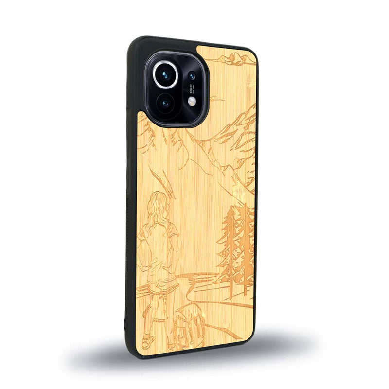 Coque de protection en bois véritable fabriquée en France pour Xiaomi Mi 11 sur le thème de la randonnée en montagne et de l'aventure avec une gravure représentant une femme de dos face à un paysage de nature