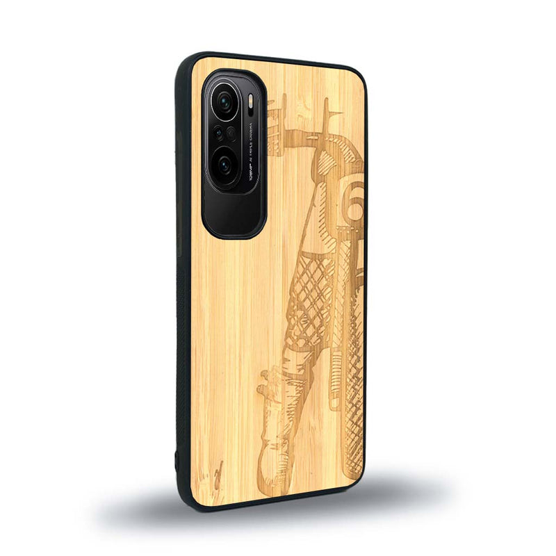 Coque de protection en bois véritable fabriquée en France pour Xiaomi Mi 11i représentant une vue de face d'une femme sur une moto vintage dessinée à la main par l'artiste Maud Dabs