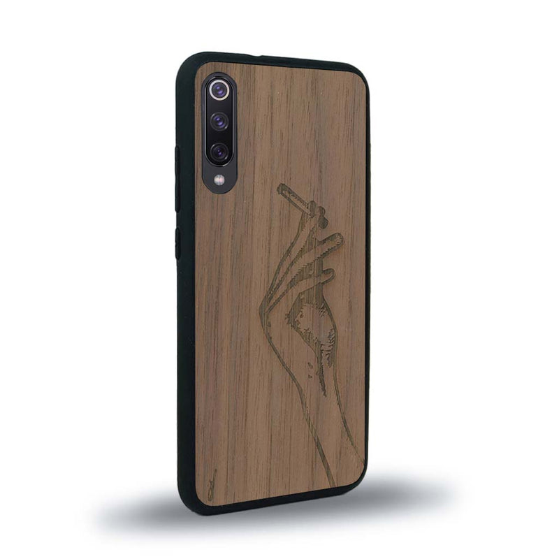 Coque de protection en bois véritable fabriquée en France pour Xiaomi Mi 9SE représentant une main de femme tenant une cigarette de type line art en collaboration avec l'artiste Maud Dabs