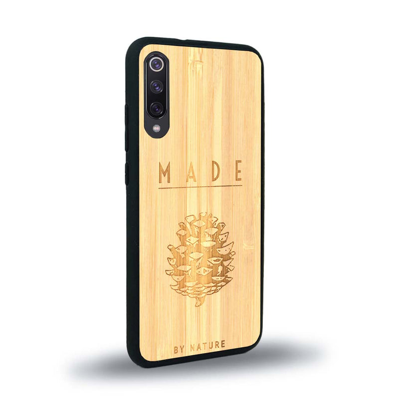 Coque de protection en bois véritable fabriquée en France pour Xiaomi Mi 9SE sur le thème de la nature et des arbres avec une gravure représentant une pomme de pin et la phrase "made by nature"