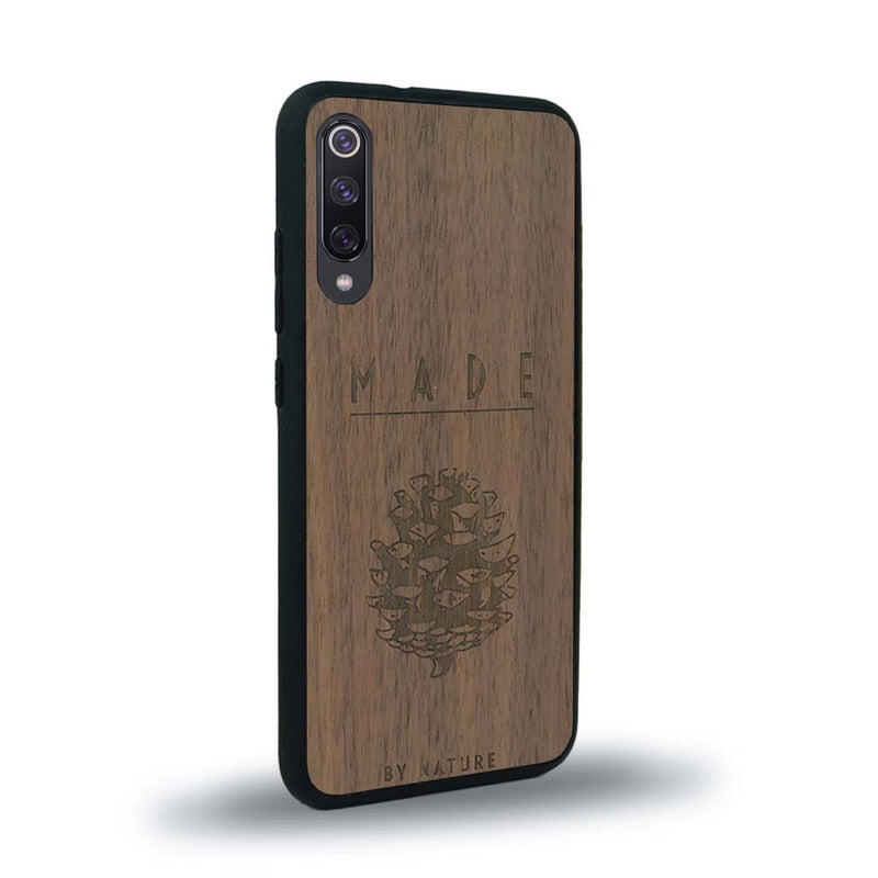 Coque de protection en bois véritable fabriquée en France pour Xiaomi Mi 9SE sur le thème de la nature et des arbres avec une gravure représentant une pomme de pin et la phrase "made by nature"