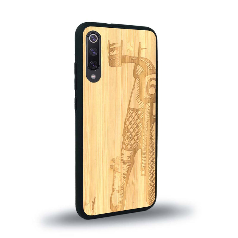 Coque de protection en bois véritable fabriquée en France pour Xiaomi Mi 9SE représentant une vue de face d'une femme sur une moto vintage dessinée à la main par l'artiste Maud Dabs