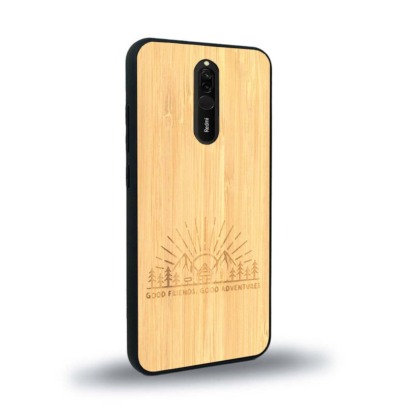 Coque de protection en bois véritable fabriquée en France pour Xiaomi Redmi 8 sur le thème chill et nature avec un motif représentant un levé de soleil sur un paysage de montagne avec des sapins et un chalet et la phrase "Good friends, good adventure"