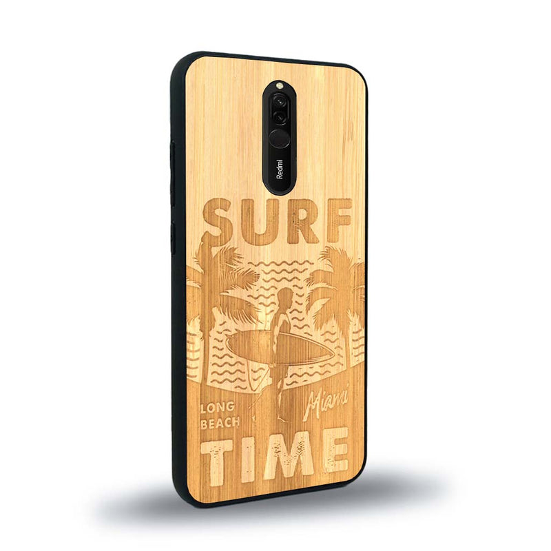 Coque de protection en bois véritable fabriquée en France pour Xiaomi Redmi 8 sur le thème chill avec un motif représentant une silouhette tenant une planche de surf sur une plage entouré de palmiers et les mots "Surf Time Long Beach Miami"