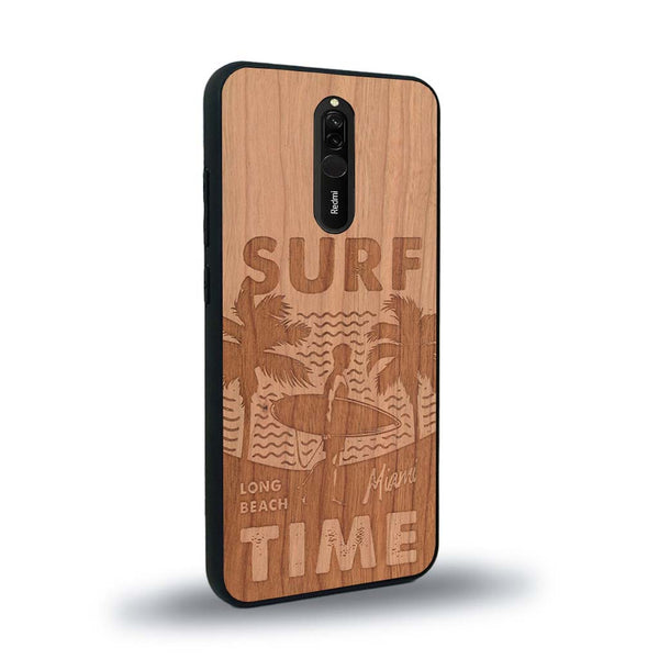 Coque de protection en bois véritable fabriquée en France pour Xiaomi Redmi 8 sur le thème chill avec un motif représentant une silouhette tenant une planche de surf sur une plage entouré de palmiers et les mots "Surf Time Long Beach Miami"