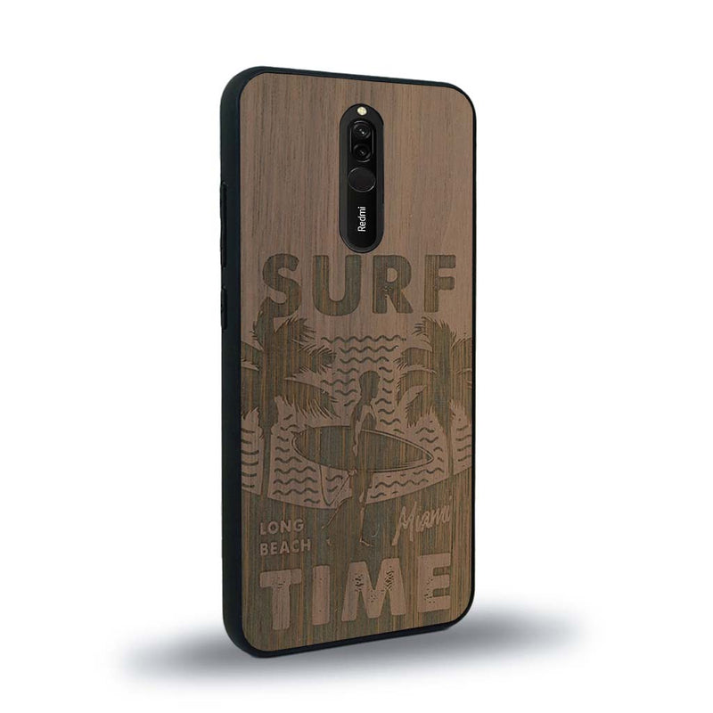 Coque de protection en bois véritable fabriquée en France pour Xiaomi Redmi 8 sur le thème chill avec un motif représentant une silouhette tenant une planche de surf sur une plage entouré de palmiers et les mots "Surf Time Long Beach Miami"