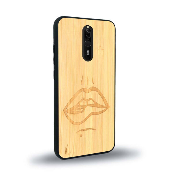 Coque de protection en bois véritable fabriquée en France pour Xiaomi Redmi 8 représentant de manière minimaliste une bouche de féminine se mordant le coin de la lèvre de manière sensuelle dessinée à la main par l'artiste Maud Dabs