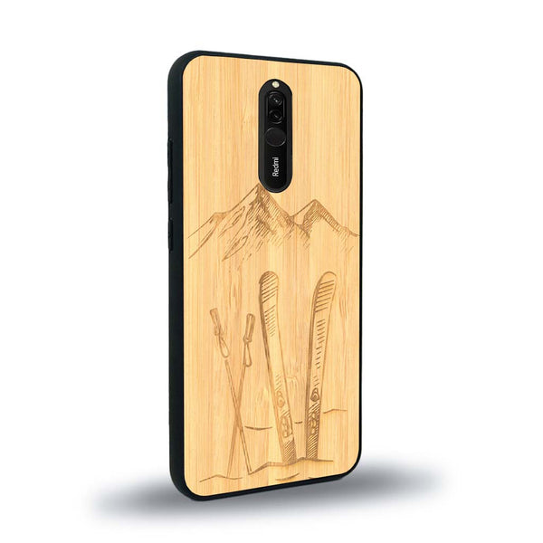 Coque de protection en bois véritable fabriquée en France pour Xiaomi Redmi 8 sur le thème de la montagne, du ski et de la neige avec un motif représentant une paire de ski plantée dans la neige avec en fond des montagnes enneigées