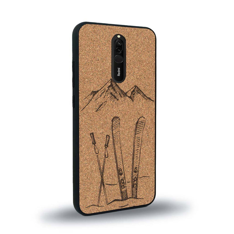 Coque de protection en bois véritable fabriquée en France pour Xiaomi Redmi 8 sur le thème de la montagne, du ski et de la neige avec un motif représentant une paire de ski plantée dans la neige avec en fond des montagnes enneigées