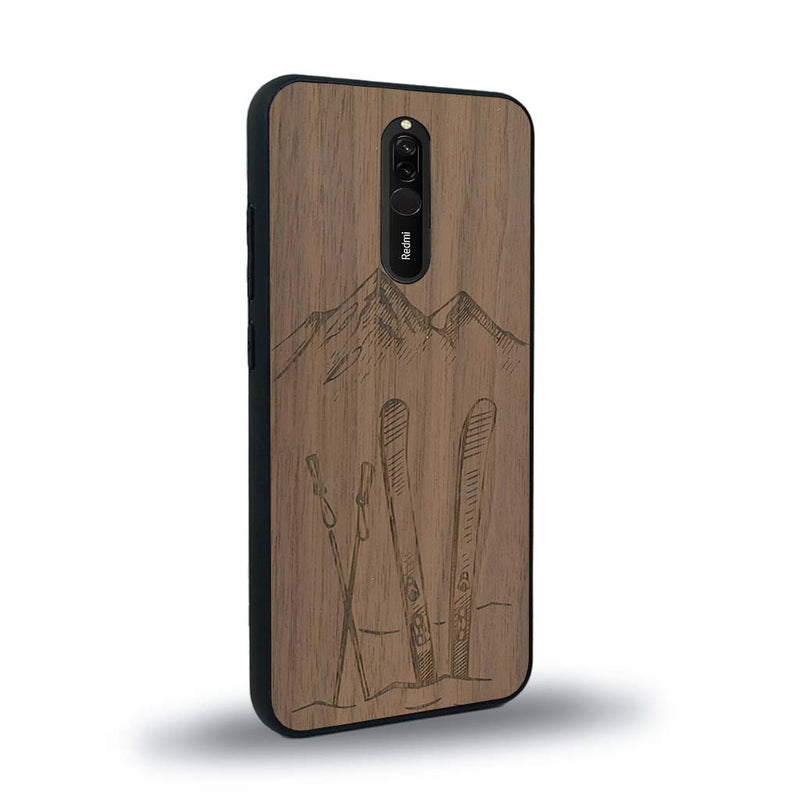 Coque de protection en bois véritable fabriquée en France pour Xiaomi Redmi 8 sur le thème de la montagne, du ski et de la neige avec un motif représentant une paire de ski plantée dans la neige avec en fond des montagnes enneigées